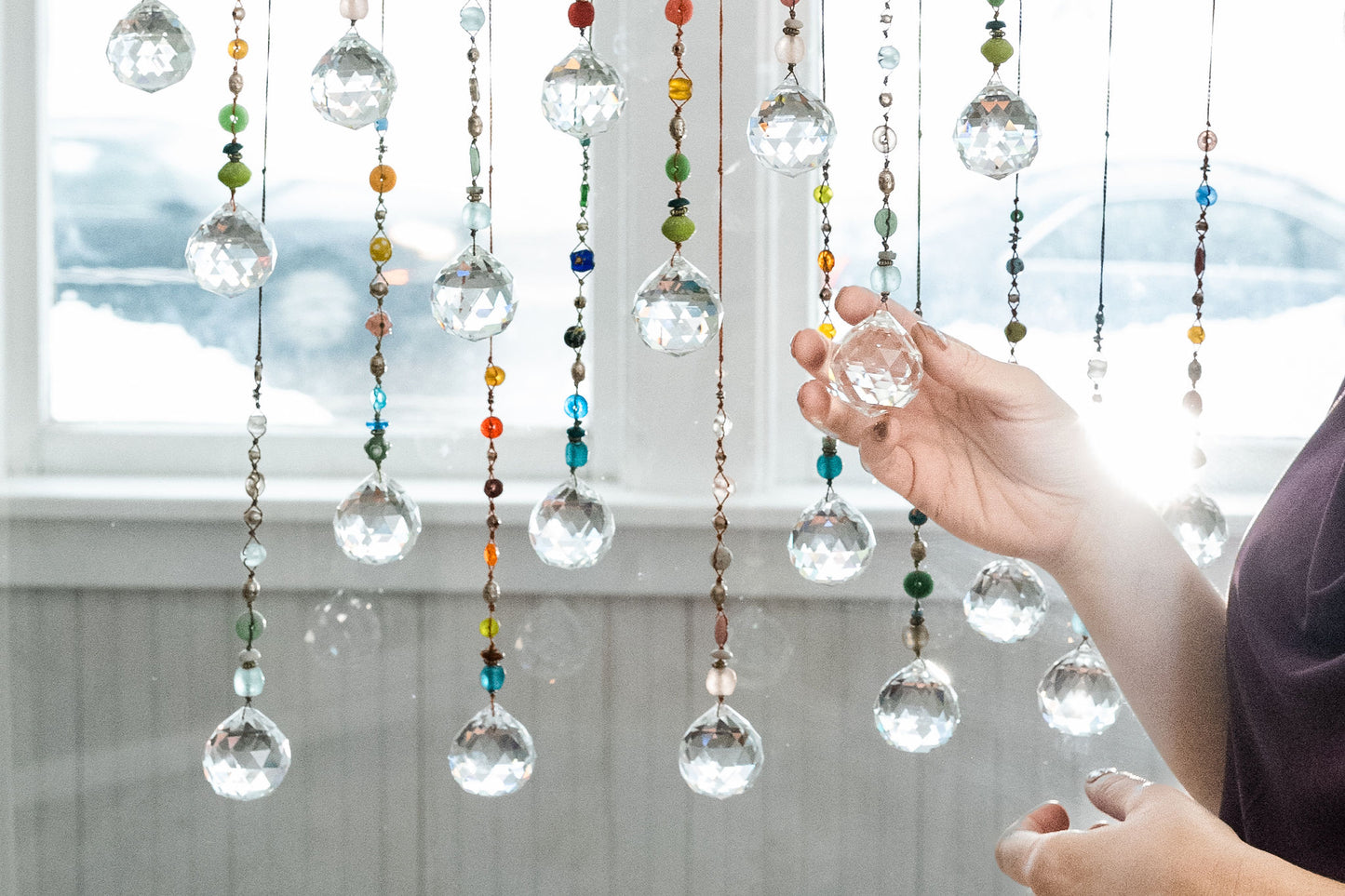 Suncatchers made with colorful beads hanging in a window. 